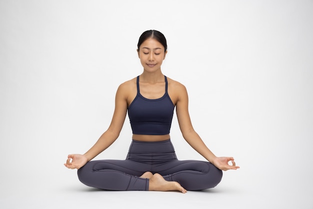 Joven mujer asiática haciendo práctica de yoga aislado sobre fondo blanco.