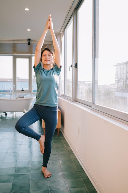 Joven mujer asiática haciendo yoga en casa