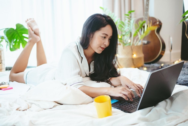 Joven mujer asiática independiente que trabaja en el trabajo de negocios en una computadora portátil en casa trabajando desde el concepto de hogar