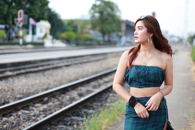 joven mujer asiática mirando a otro lado en la estación de tren con cara de belleza