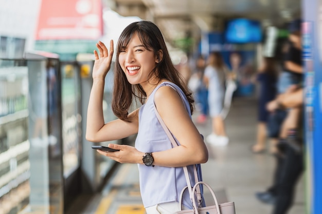 Joven mujer asiática pasajero agitando la mano para saludar a su amiga en el metro