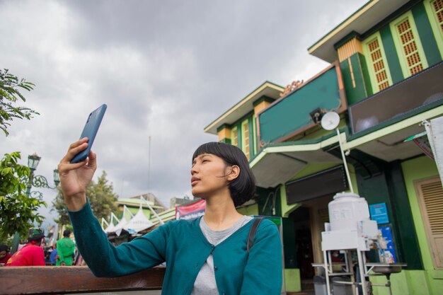 Joven mujer asiática selfie con teléfono móvil en espacios públicos