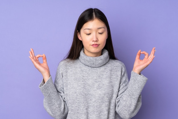 Joven mujer asiática sobre antecedentes aislados en pose zen