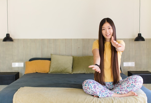 Joven mujer asiática sonriendo con orgullo y confianza, sintiéndose feliz y satisfecha y mostrando un concepto en el espacio de la copia