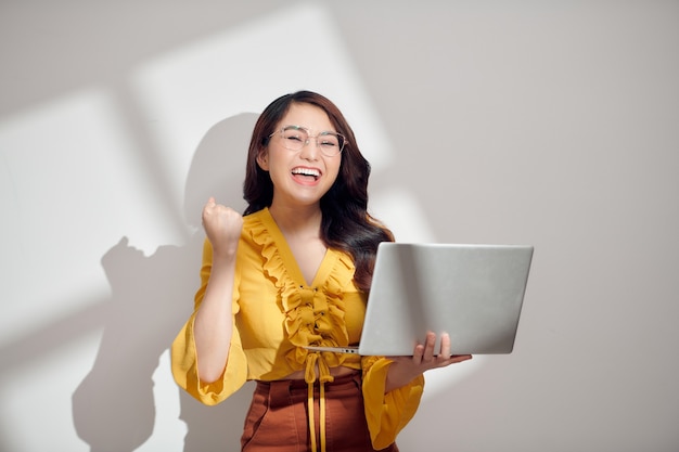 Joven, mujer asiática, sonriente, tenencia, computadora de computadora portátil