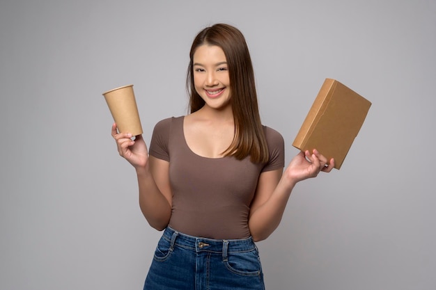 Joven mujer asiática sosteniendo un vaso de papel y una caja de papel sobre fondo blanco Concepto de salvar la tierra