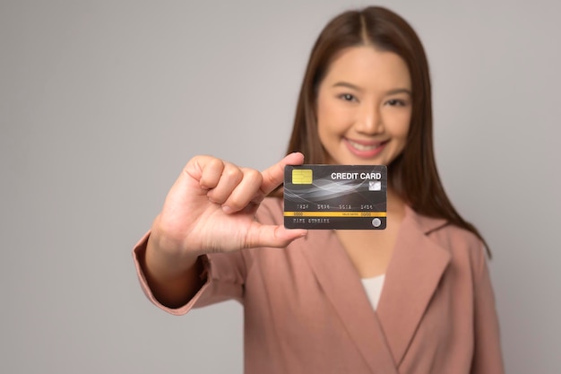 Joven mujer asiática con tarjeta de crédito sobre concepto de compras y finanzas de estudio de fondo blanco