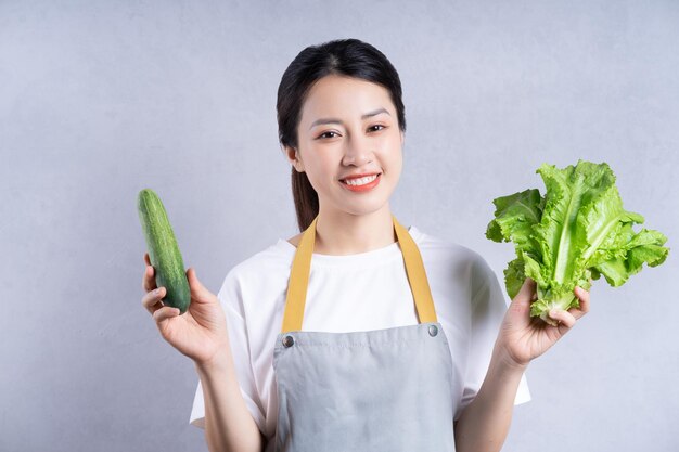 joven, mujer asiática, tenencia, vegetales, en, plano de fondo