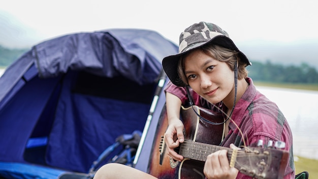 Foto joven mujer asiática tocando la guitarra en el camping