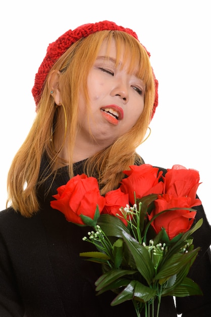Joven mujer asiática triste sosteniendo rosas rojas y mirando a otro lado