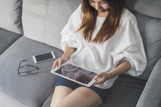 Joven mujer asiática usando tableta en casa