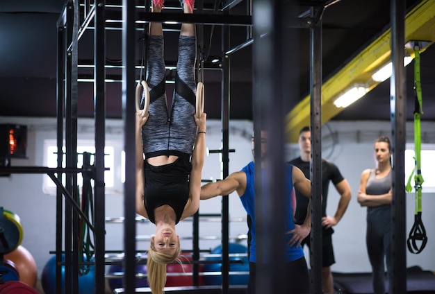 joven mujer atlética trabajando con entrenador personal en anillos de gimnasia en el gimnasio cross fitness