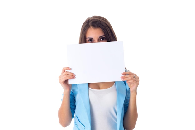 Joven mujer atractiva con chaqueta azul escondiendo la mitad de su rostro con una hoja de papel blanca