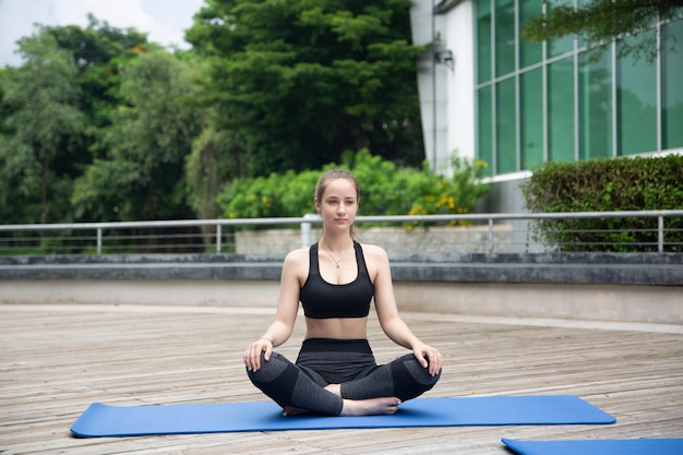 Joven mujer atractiva deportiva practicando yoga haciendo ejercicio de yoga Hermosa mujer joven practicando yoga en la terraza de madera