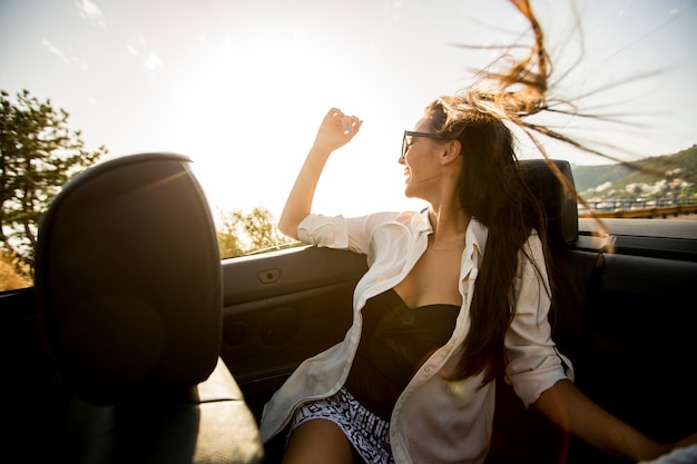 Foto joven mujer atractiva posa en cabriolet en la playa