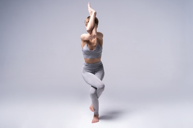 Joven mujer atractiva sonriente practicando yoga