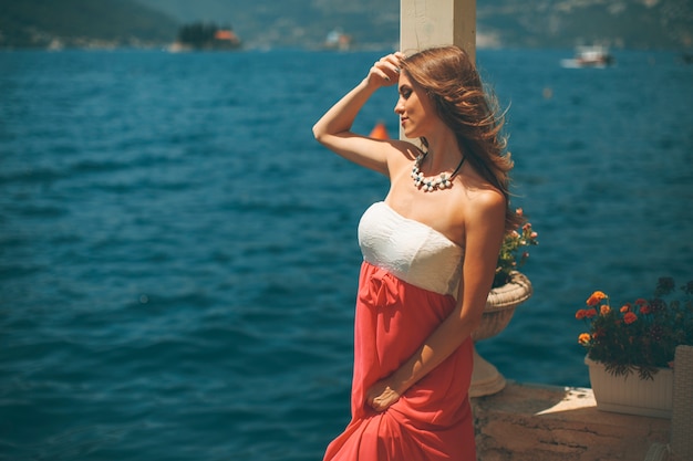 Joven mujer atractiva en un vestido de relax junto al mar en un día soleado