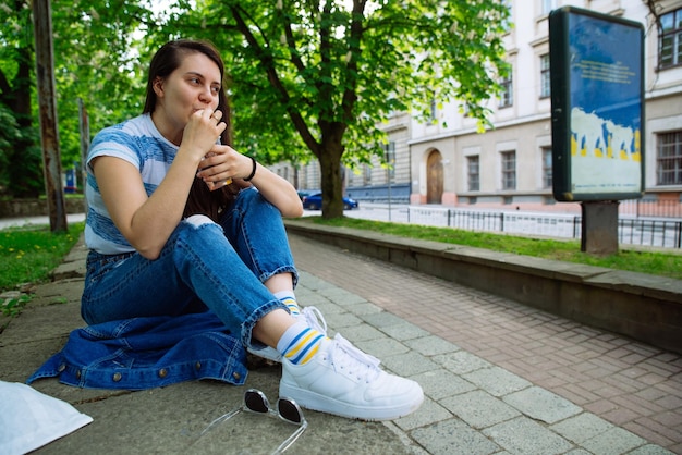 Joven mujer bastante alegre comer naranja de bebida fría de limonada para llevar