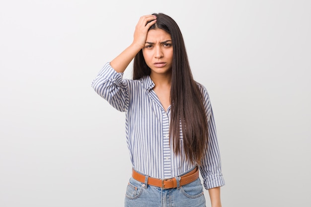 Foto joven mujer bastante árabe cansada y con mucho sueño manteniendo la mano en la cabeza.