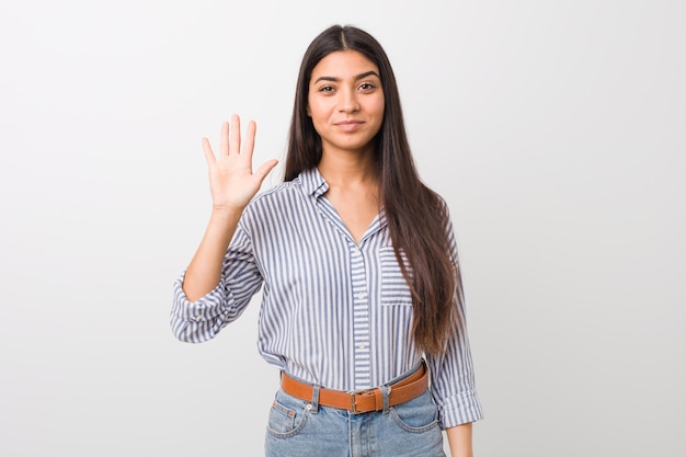 Joven mujer bastante árabe sonriendo alegre mostrando número cinco con los dedos.