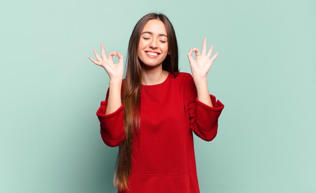 Joven mujer bastante casual que parece concentrada y meditando, sintiéndose satisfecha y relajada, pensando o haciendo una elección