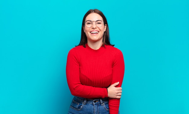 Joven mujer bastante casual riendo tímidamente y alegremente, con una actitud amistosa y positiva pero insegura