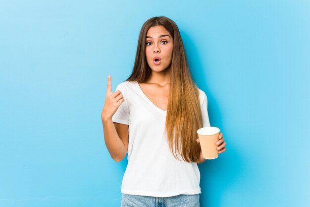 Joven mujer bastante caucásica sosteniendo un café para llevar con una gran idea, concepto de creatividad.