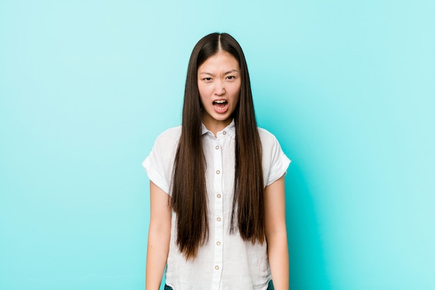 Joven mujer bastante china gritando muy enojado y agresivo.