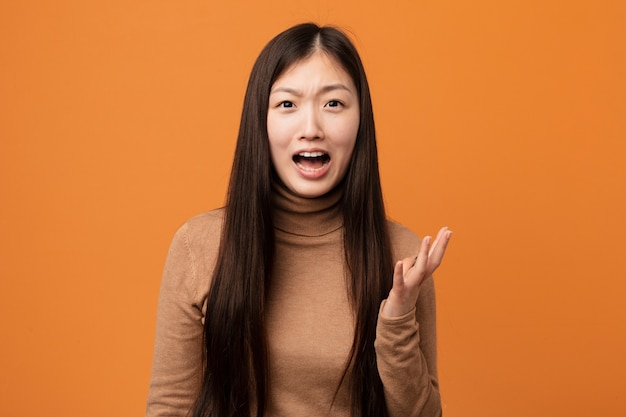 Joven mujer bastante china gritando de rabia.