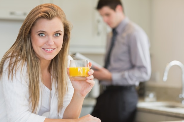 Joven mujer bebiendo jugo de naranja en la cocina