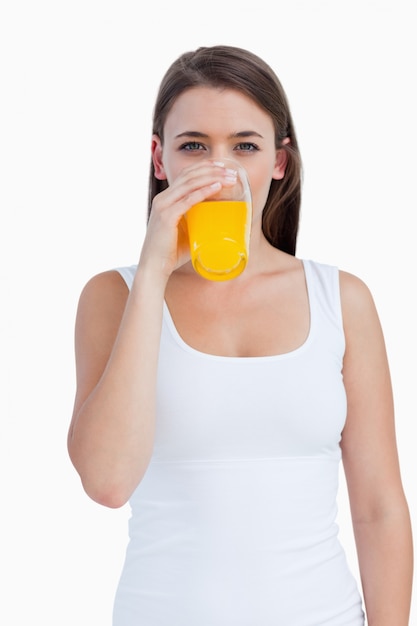 Joven mujer bebiendo un jugo de naranja