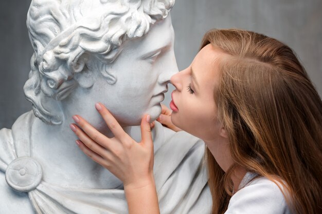 Joven mujer besando a Dios Apolo busto escultura.