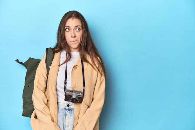 Foto joven mujer blanca viajera con cámara y mochila confundida se siente dudosa e insegura