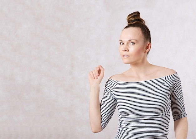 Una joven mujer bonita de entre 30 y 40 años vestida con una camisa gris blanca con mangas largas.