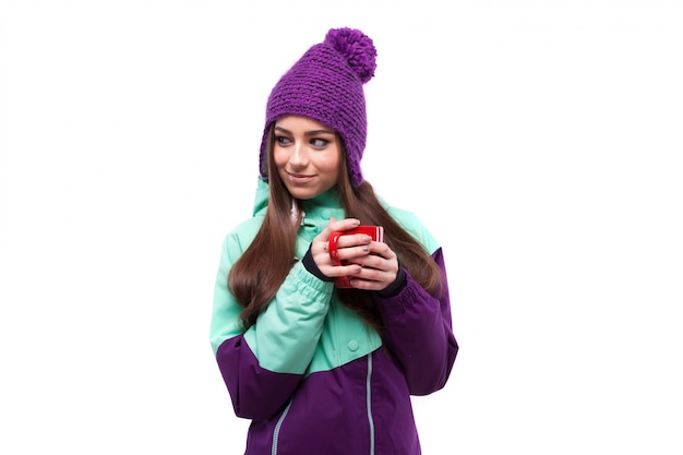 Joven mujer bonita en abrigo de esquí púrpura mantenga copa