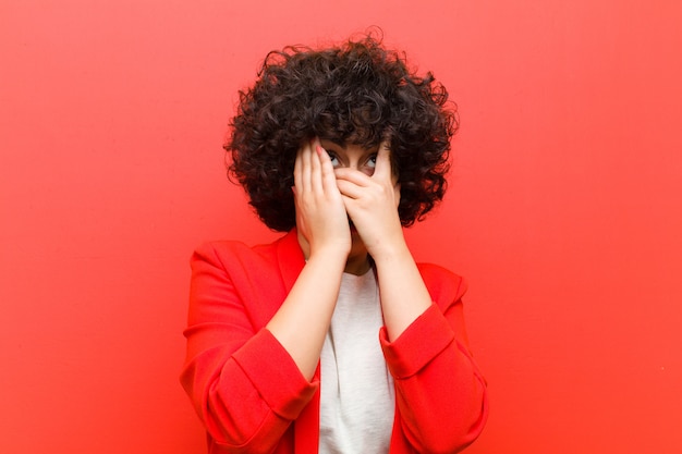 Joven mujer bonita afro cubriéndose la cara con las manos