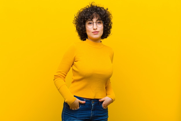 Joven mujer bonita afro sonriendo alegremente y casualmente con una expresión positiva, feliz, segura y relajada