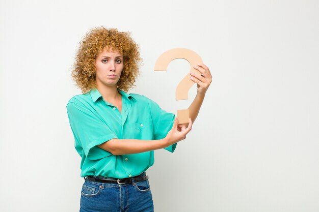 Foto joven mujer bonita afro triste, deprimido, infeliz, sosteniendo el? símbolo para formar una palabra o una oración.