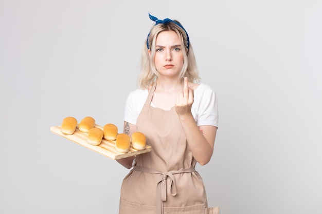 Joven mujer bonita albina que se siente enojada, molesta, rebelde y agresiva con una bandeja de bollos de pan