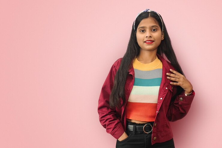 Joven mujer bonita asiática india que se siente feliz y enamorada sonriendo con una mano al lado del corazón y la otra en el bolsillo con espacio para copiar