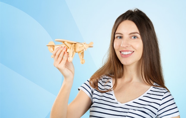 Joven mujer bonita con un avión de juguete de madera