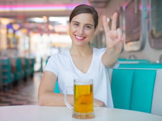 joven mujer bonita bebiendo una pinta de cerveza en un restaurante de cena americano