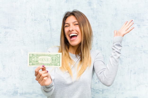 Joven mujer bonita con billetes contra la pared del grunge