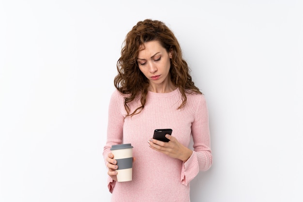 Joven mujer bonita con café para llevar y un móvil