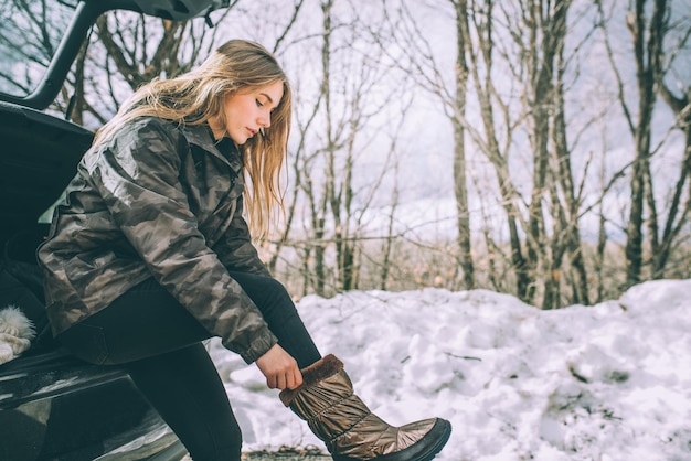 Joven mujer bonita en una carretera con nieve en invierno