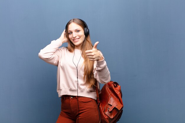 Joven mujer bonita contra la pared azul con un espacio de copia