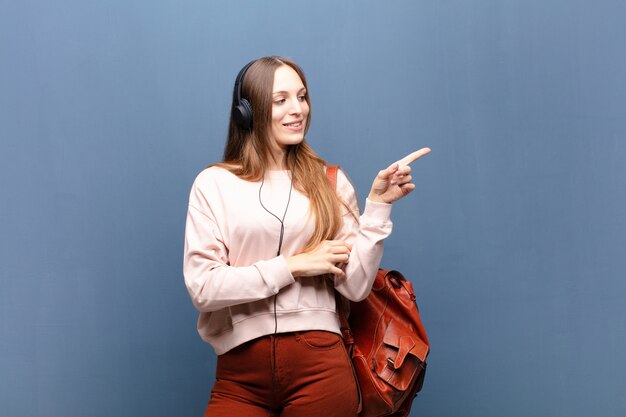 Joven mujer bonita contra la pared azul con un espacio de copia