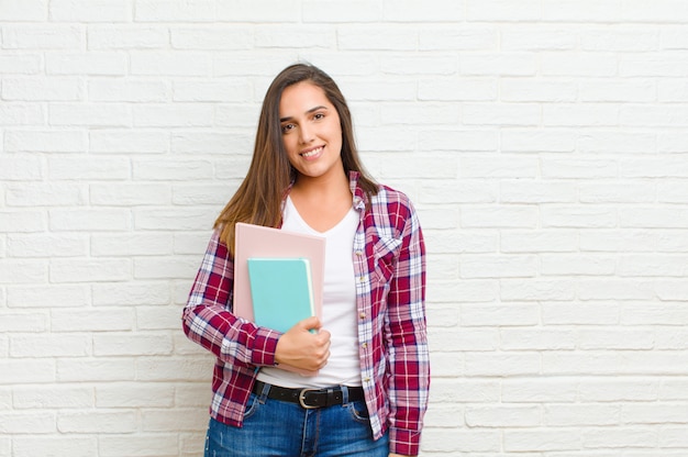 Joven mujer bonita contra la textura de la pared de ladrillo