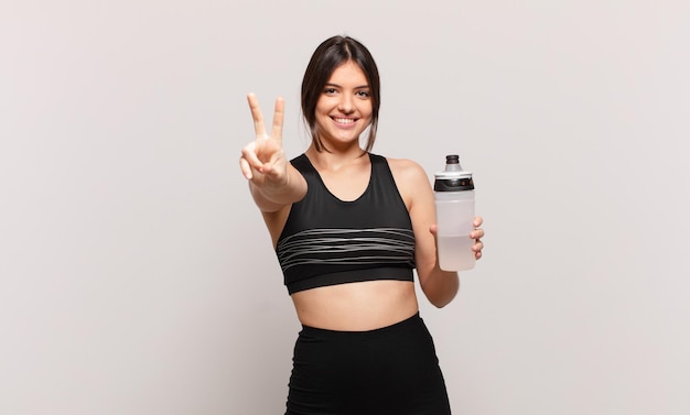 Joven mujer bonita del deporte celebrando una victoria exitosa y sosteniendo una bebida de botella de agua