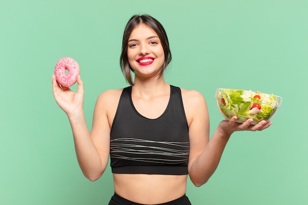 Foto joven mujer bonita deporte expresión feliz y sosteniendo una ensalada